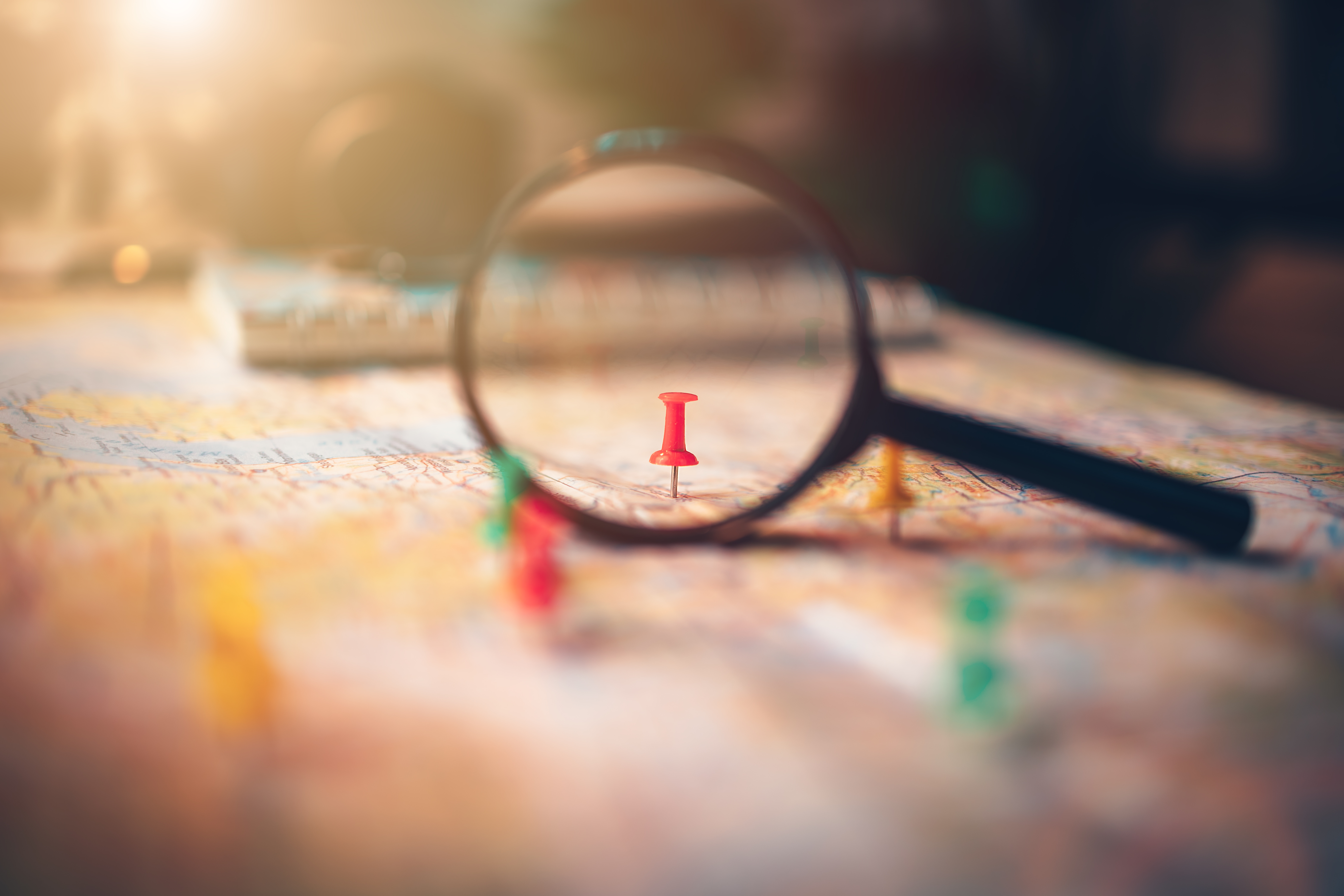 A magnifying glass with pins pinned on the map. pushpin showing the location of a destination point on a map. Travel plan concept.
