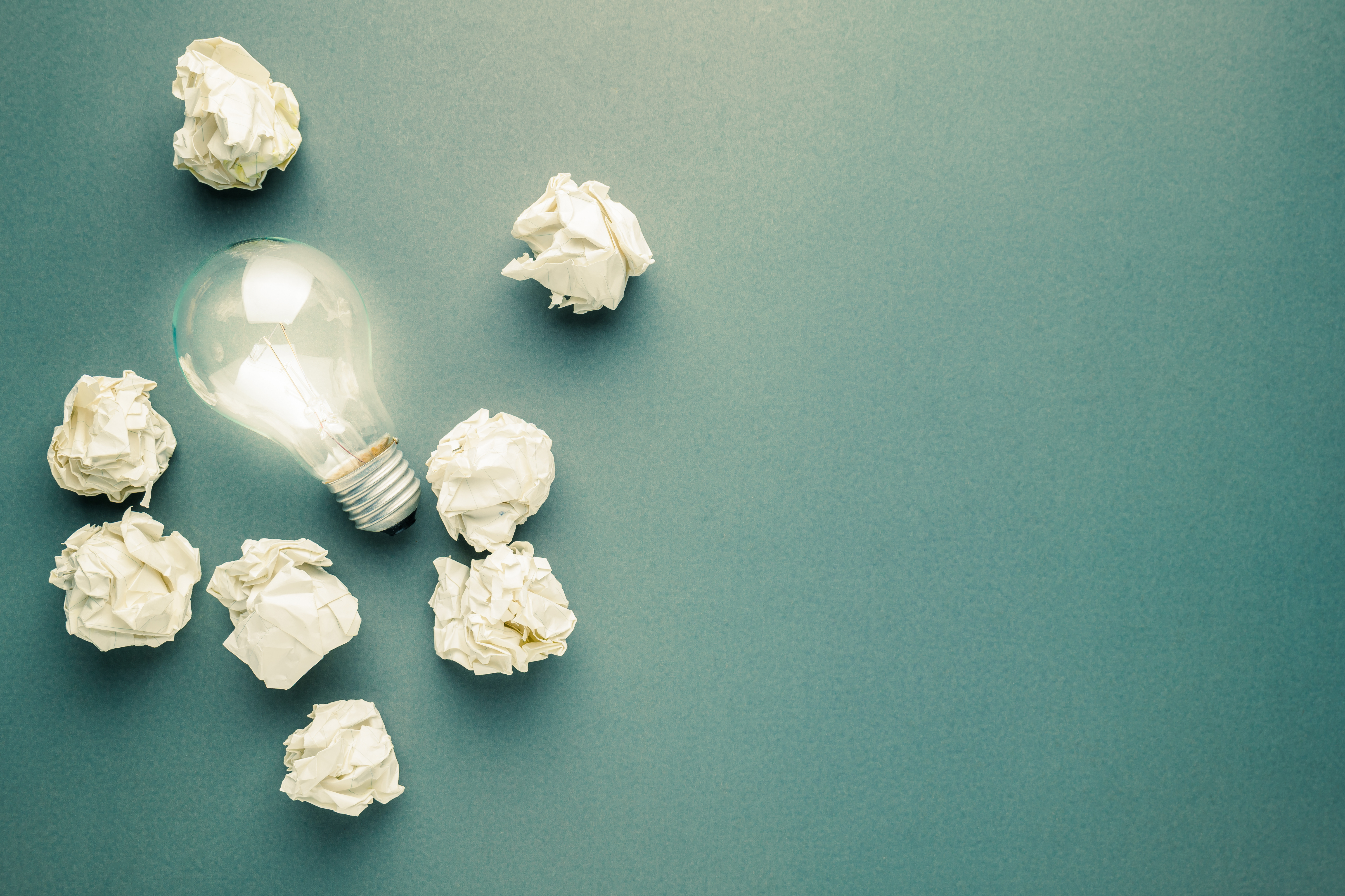 Glowing light bulb in the group of trash paper balls, lesson learned, learn from mistake concept